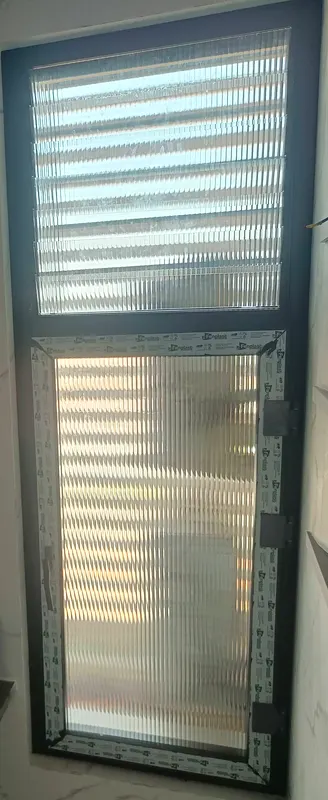 Dark-frame bathroom window with glass louvres above an openable reeded-glass sash