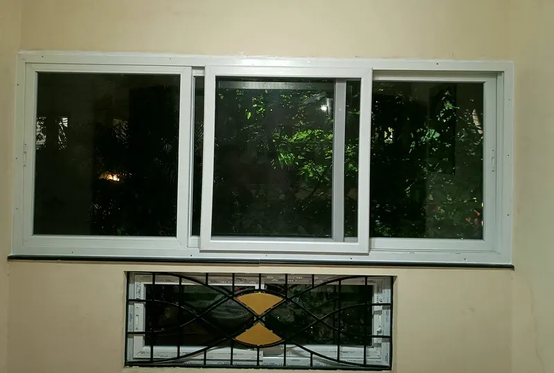 Three-track uPVC sliding window in a bedroom wall