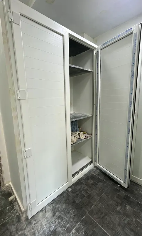 Built-in white uPVC wardrobe with two hinged doors open to show shelves